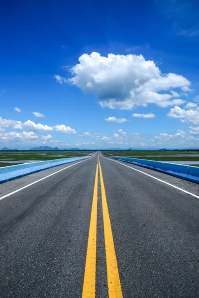 Boş yol ve trafik sarı çizgileri mavi gökyüzü ile. — Stok fotoğraf