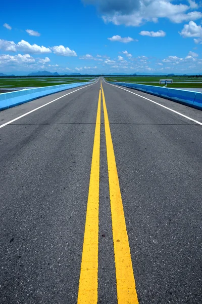 Strada vuota e le linee di traffico gialle con cielo blu . — Foto Stock