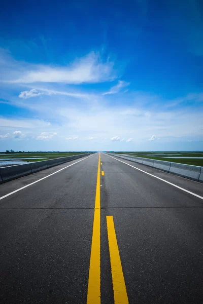 Boş yol ve trafik sarı çizgileri mavi gökyüzü ile. — Stok fotoğraf
