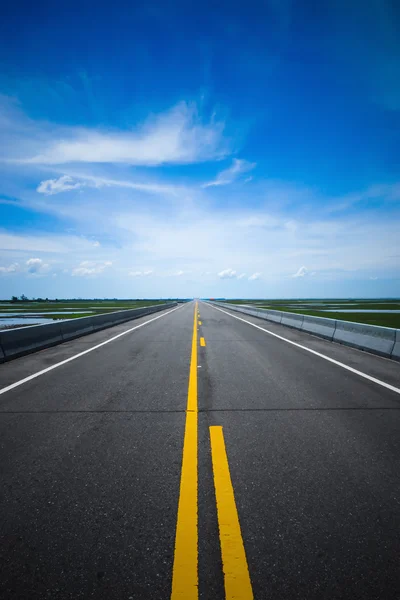 Leere Straße und die gelben Verkehrslinien mit blauem Himmel. — Stockfoto