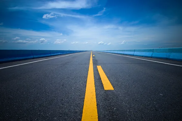 Leere Straße und die gelben Verkehrslinien mit blauem Himmel. — Stockfoto