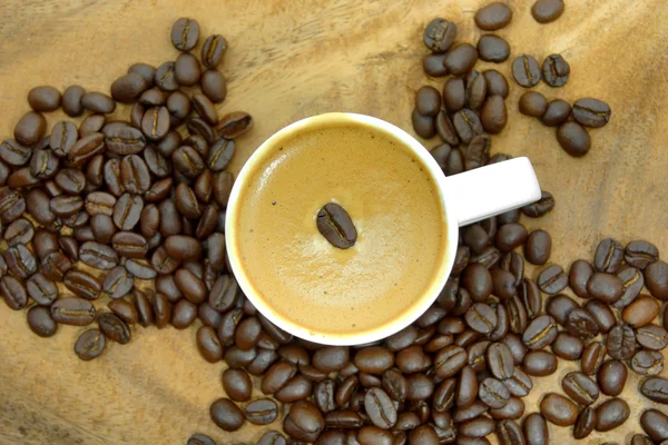 Grão de café e café em fundo de madeira — Fotografia de Stock