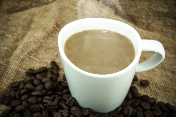 Kaffee und Kaffeebohnen auf handgemachtem Stoff. — Stockfoto