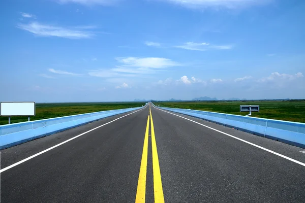 ถนนที่ว่างเปล่าและเส้นทางการจราจรสีเหลืองที่มีท้องฟ้าสีฟ้า . — ภาพถ่ายสต็อก