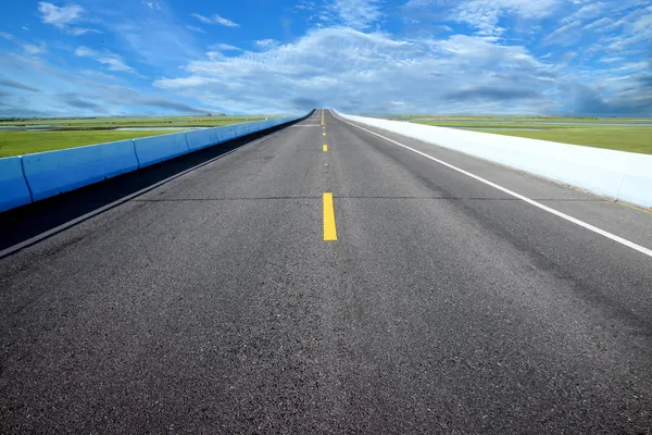 Boş yol ve trafik sarı çizgileri mavi gökyüzü ile. — Stok fotoğraf