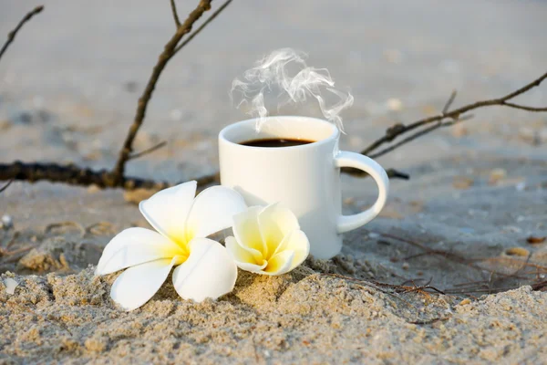 Coffee on the beach and frangipani flower. — Stock Photo, Image