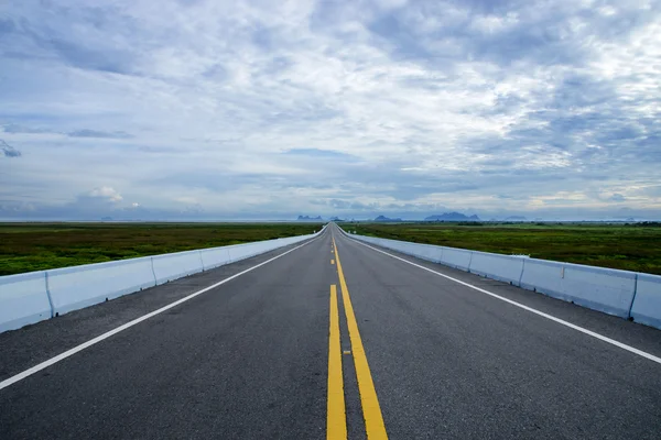 Carretera vacía y las líneas de tráfico amarillas con nubes . —  Fotos de Stock