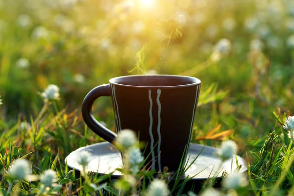 's ochtends koffie met zwarte kop in de bloem gras achtergrond. — Stockfoto