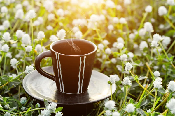 Café du matin avec tasse noire dans le fond de l'herbe de fleur . — Photo