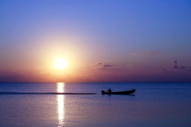Gün batımında göl kenarında bir balıkçı teknesinin silueti..