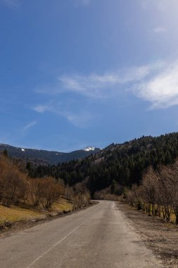 Yol, dağlar ve arkadaki mavi gökyüzü 