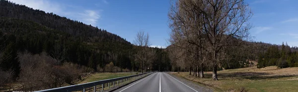 Empty road, mountains and trees with sky at background, banner 