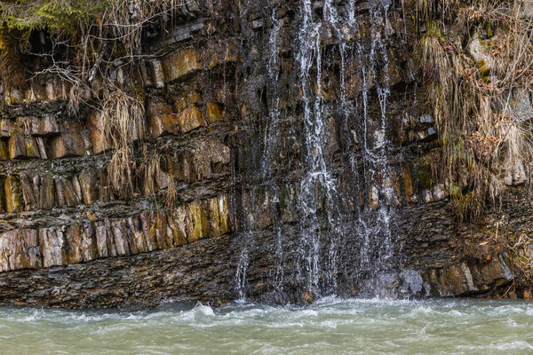 Mountain creek and wooden roots on hill with stones 