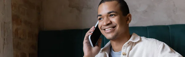 Sonriente Joven Hombre Afroamericano Hablando Teléfono Inteligente Cafetería Bandera —  Fotos de Stock