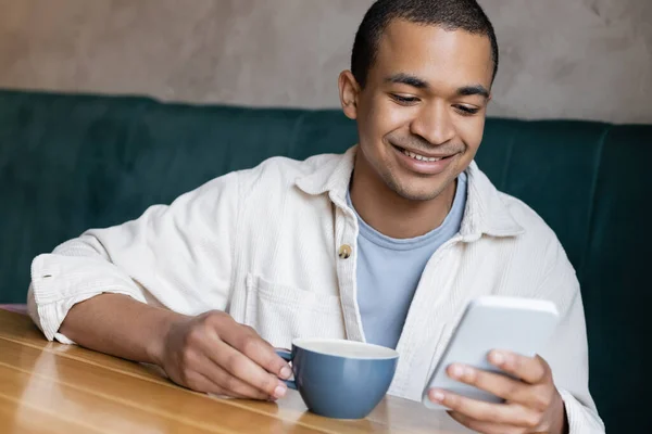 웃으며 아프리카 미국인 남자가 샵에서 스마트폰으로 문자를 보내고 있습니다 — 스톡 사진