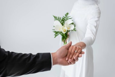 Gri renkte izole edilmiş damat ile el ele tutuşmuş gelin manzarası. 