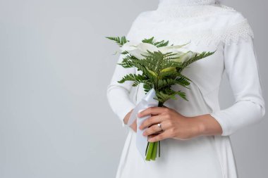 Beyaz elbiseli bir kadının gri renkte izole bir gelin buketi taşıdığı görüntüler.