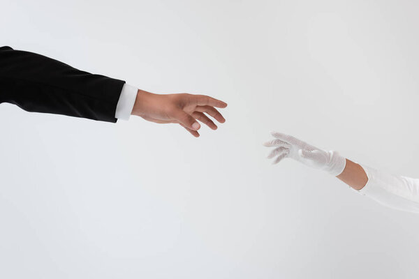 cropped view of groom and bride reaching each other hands isolated on grey 