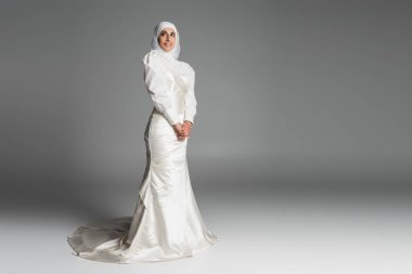 Gelinlik ve tesettür içinde koyu gri üzerinde duran Müslüman gelinin tam uzunluğu 