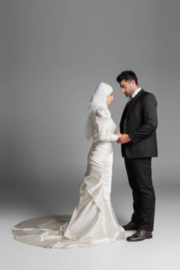 Gelinlikli Müslüman gelin ve takım elbiseli damat el ele tutuşuyor.
