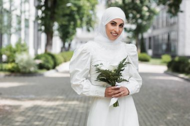 Elmas yüzüklü neşeli Müslüman gelin elinde düğün buketi tutuyor. 