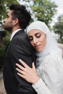 Mutlu Müslüman gelin tesettüre ve gelinliğe sarılmış damat 