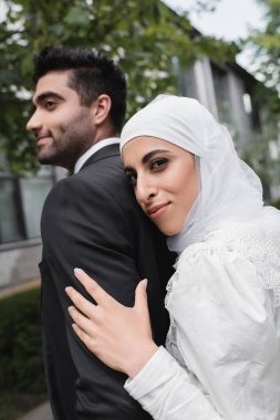 Neşeli Müslüman gelin tesettüre ve gelinliğe sarılmış damat. 