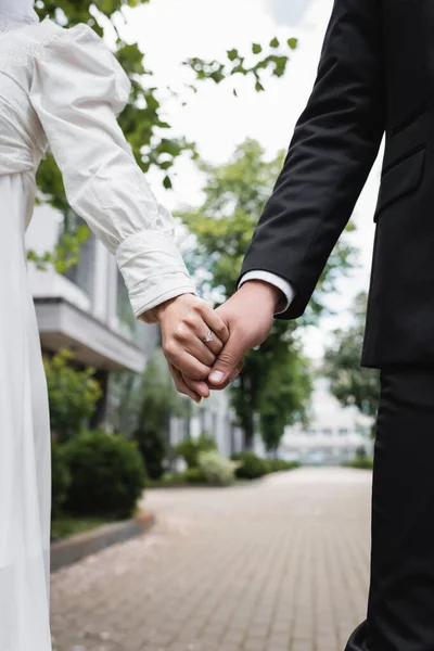 Przycięty Widok Nowożeńców Sukni Ślubnej Formalnym Ubraniu Trzymających Się Ręce — Zdjęcie stockowe