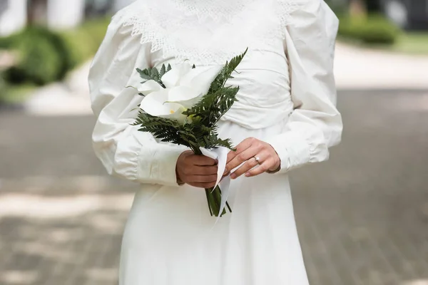 cropped view of bride with diamond ring on finger holding wedding bouquet