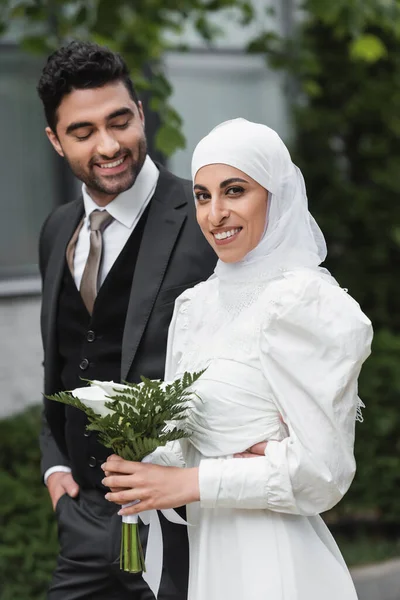 Веселый Жених Смотрит Мусульманскую Невесту Свадебном Хиджабе Белом Платье Букетом — стоковое фото