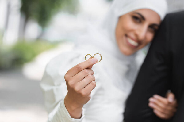 happy and blurred muslim bride holding wedding golden rings in hand