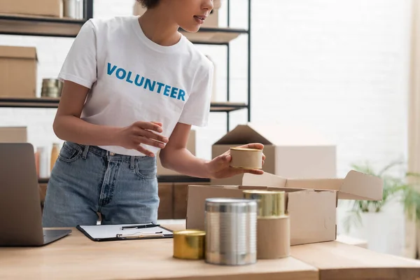 Cropped View African American Woman Sorting Canned Foodstuff Volunteer Warehouse — Stock fotografie