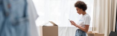 side view of african american volunteer using mobile phone in donation center, banner