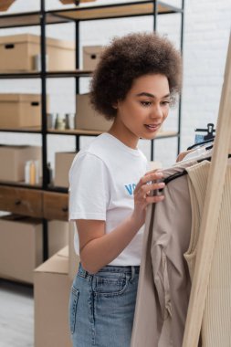 Genç Afrikalı Amerikalı gönüllü yardım merkezinde kıyafet seçiyor.