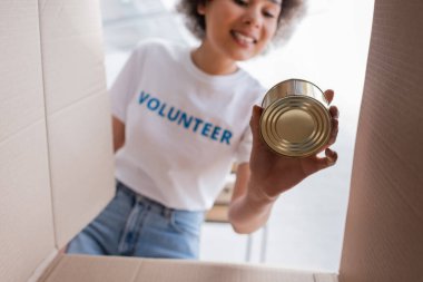 bottom view of african american volunteer holding tin near carton box
