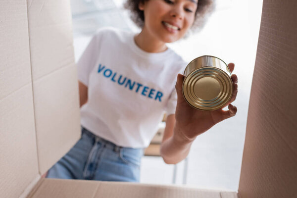 bottom view of african american volunteer holding tin near carton box