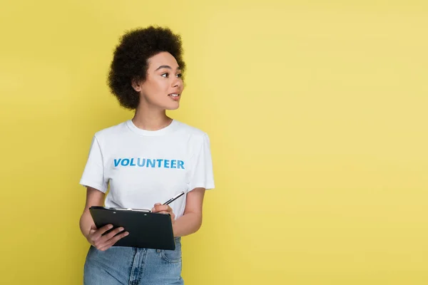 Voluntario Afroamericano Positivo Escribiendo Portapapeles Mirando Hacia Otro Lado Aislado — Foto de Stock