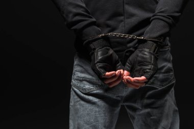 Cropped view of african american hooligan in handcuffs isolated on black  clipart