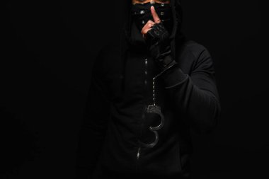 Cropped view of african american hooligan in handcuff showing secret gesture isolated on black 
