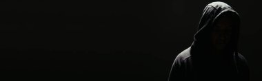 Silhouette of hooligan in hoodie with lighting isolated on black, banner 