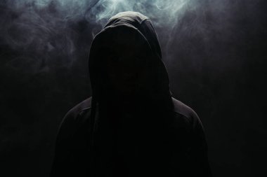 Silhouette of hooligan in hood on black background with smoke  clipart