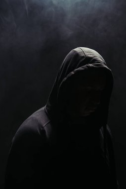 Siyah arka planda kapüşonlu, dumanlı haydut silueti 