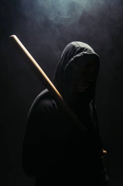 Silhouette of bandit holding baseball bat on black background with smoke  clipart