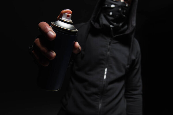 Cropped view of blurred african american hooligan holding spray paint isolated on black 