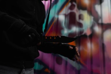 Afro-Amerikalı soyguncunun elinde bıçakla sokak ortasında graffiti yaparken çekilmiş görüntüsü. 