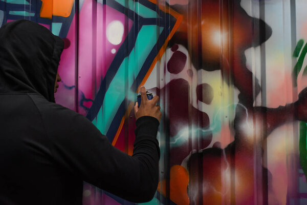 African american hooligan drawing graffiti on wall on street 