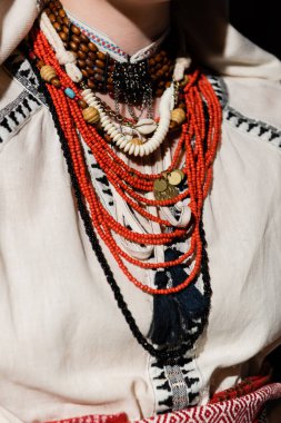 cropped view of ukrainian woman in traditional clothing with ornament and red beads 