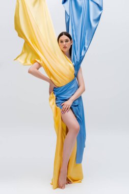 Ukrayna mavisi ve sarı elbiseli, elleri gri kalçasında poz veren güzel bir kadın.