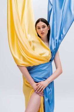 young ukrainian woman in blue and yellow dress posing isolated on grey
