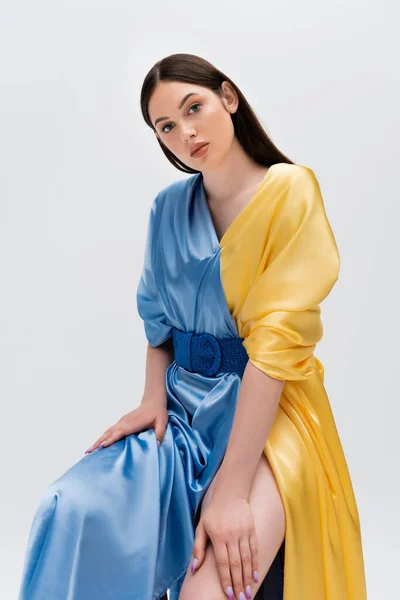 Чувственная Украинская Женщина Синем Желтом Платье Позирует Сидя Изолированно Сером — стоковое фото